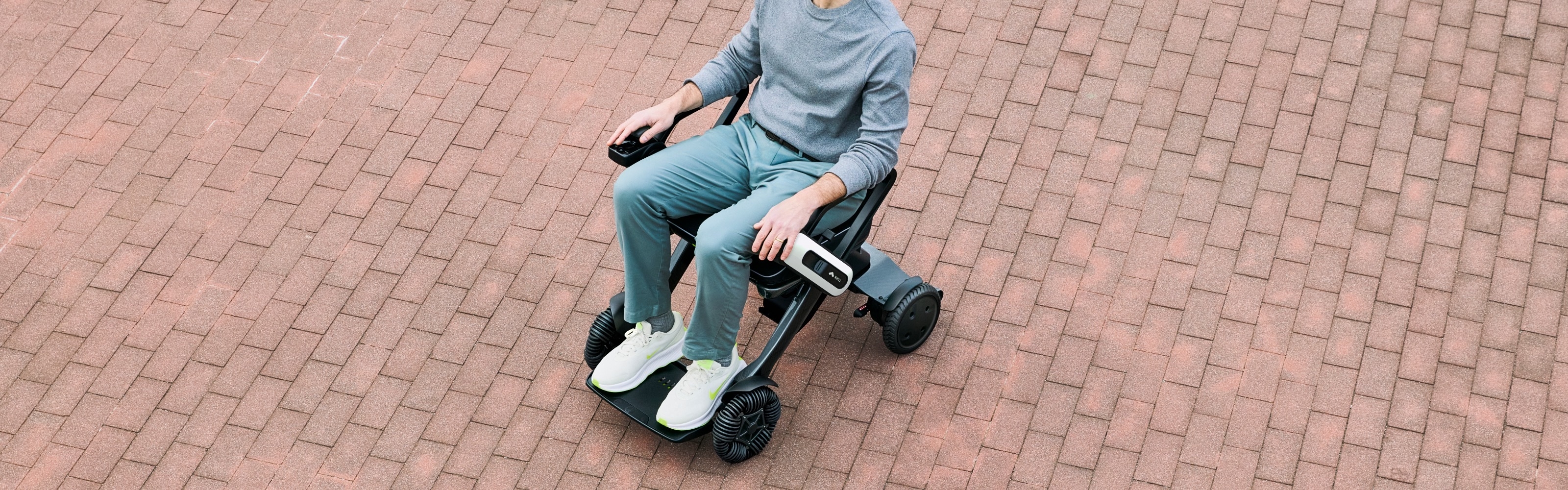 WHILL Model C Lite being ridden on brick paving