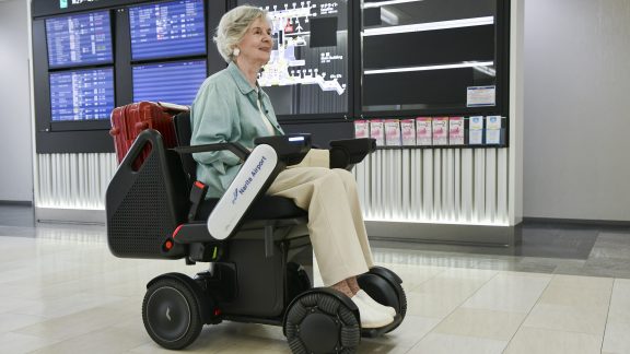 Woman rides a WHILL autonomous airport mobility device.