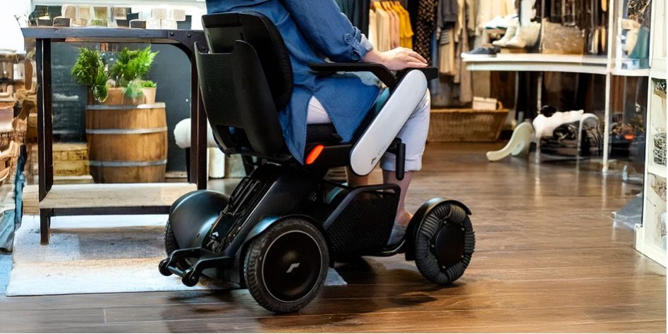 Women in a WHILL Model C2 powerchair shopping in a retail store.