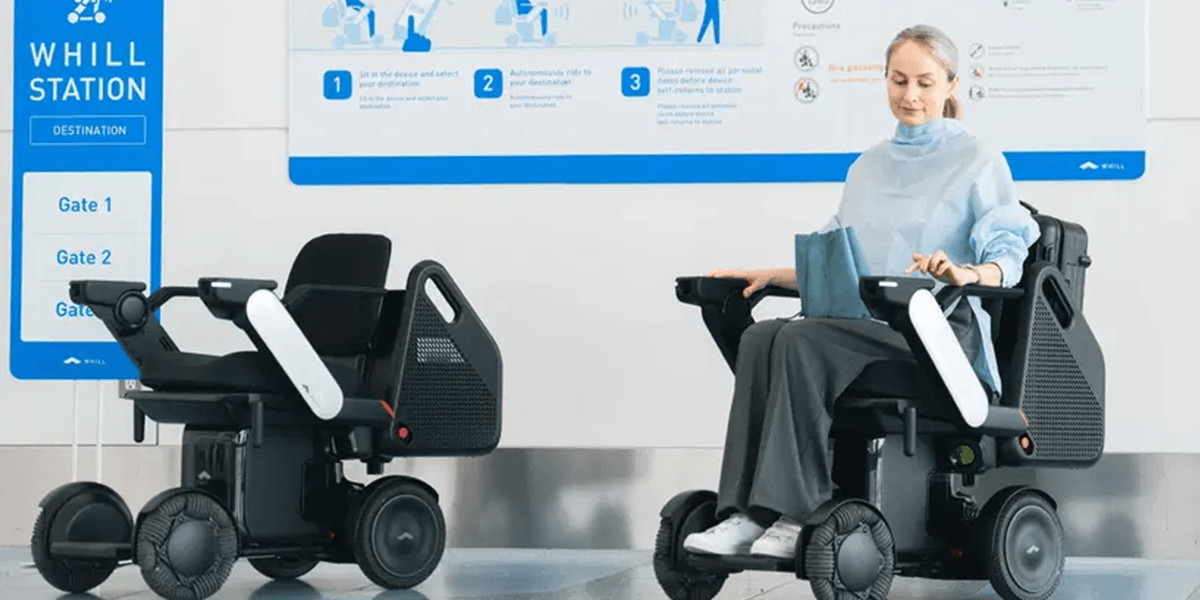 A women sitting in the WHILL autonomous service powerchair at an airport WHILL station.