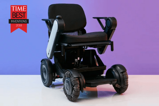 A sleek, modern power wheelchair with large, omni wheels is set against a gradient purple background. A "Time Best Inventions 2018" badge is visible, highlighting its innovative design.
