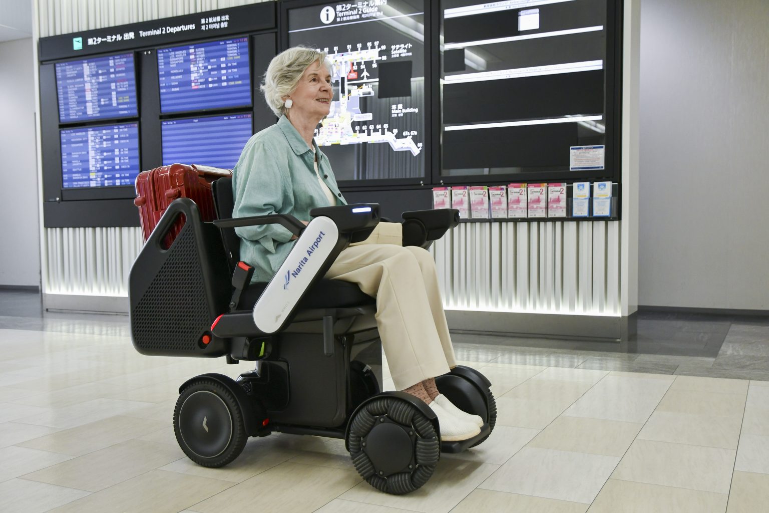 Woman rides a WHILL autonomous airport mobility device.