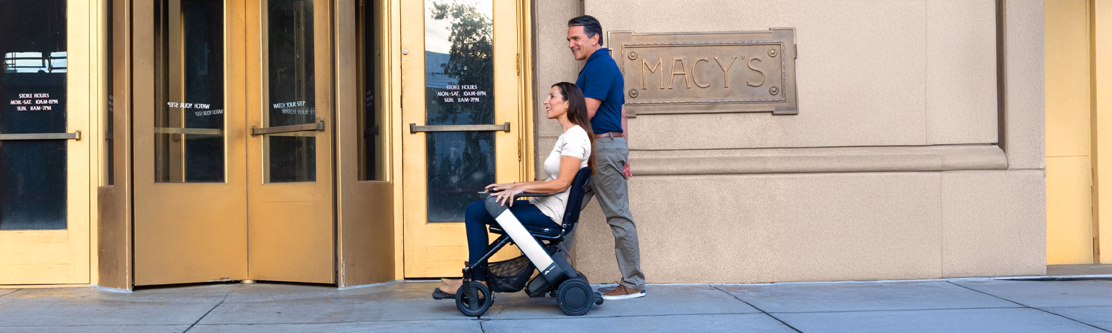 A man walking with a woman in one of WHILL's power wheelchair